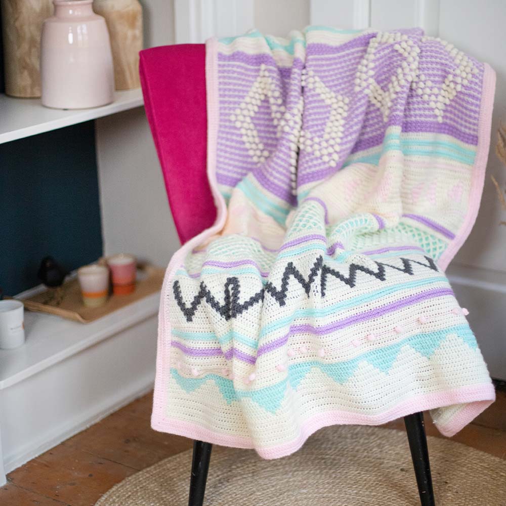 Droomdeken 6.0 in roze, mint en lila over een fauteuil