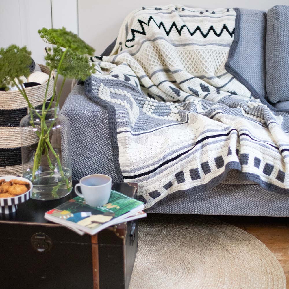 Droomdeken 6.0 in blauw, wit en grijs op een fauteuil